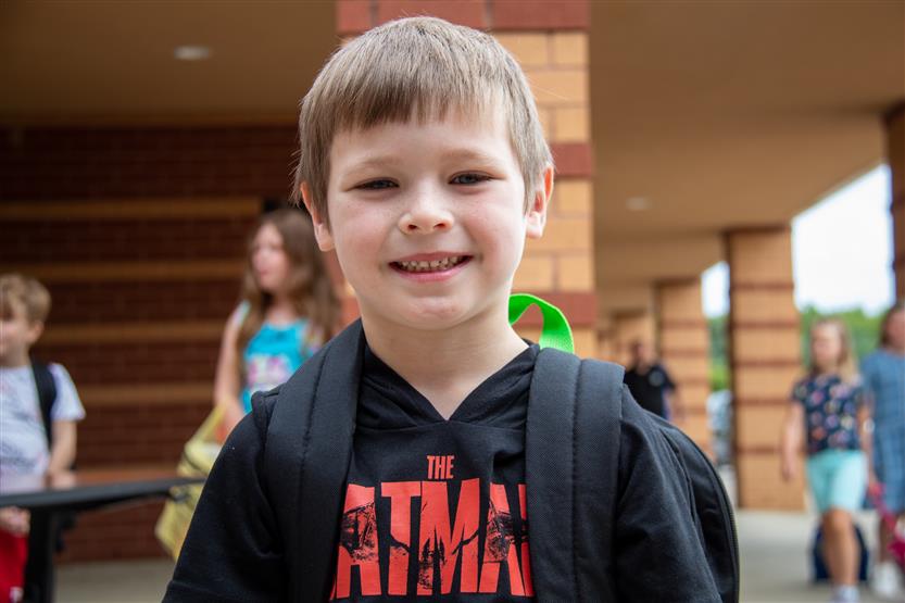 A boy wearing a dark t-shirt smiles